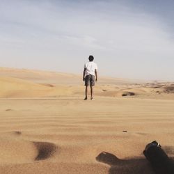 Full length rear view of man walking in desert