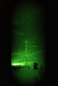 Illuminated lighting equipment on field against sky at night