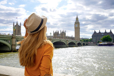 Girl enjoying sight of westminster bridge and palace on river thames with big ben tower in london,uk