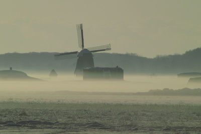 Windmill on farm against sky