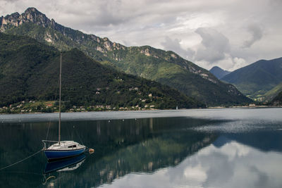 Sailboats moored on lake against mountains