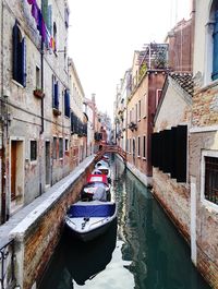 Boats moored in canal amidst buildings