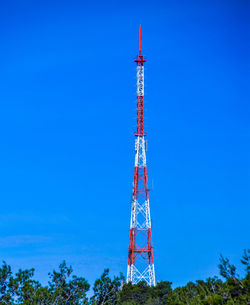 Low angle view of communications tower against blue sky