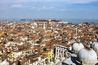 High angle view of cityscape by sea against sky during sunny day