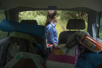 Camping equipment in car against woman standing outside