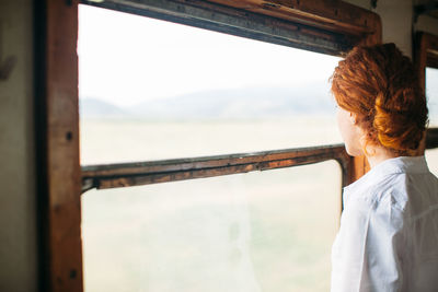 Side view of woman looking through window in train