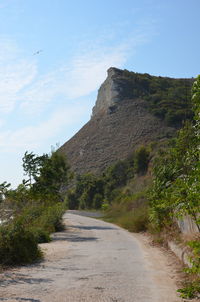 Road leading towards mountain against sky