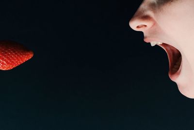 Close-up of hand holding red balloon over white background