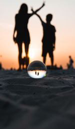 Silhouette people on beach against sky during sunset