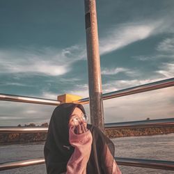 Young woman in hijab looking away against sky