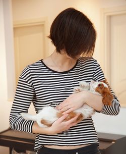 Woman holding puppy while standing at home