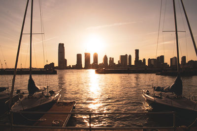 Sailboats moored in sea against sky during sunset