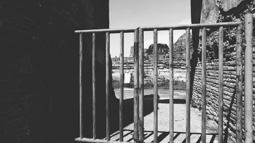 Metal fence by building against sky