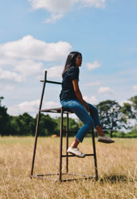 Side view of woman on field against sky