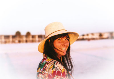 Portrait of smiling mid adult woman wearing hat against clear sky