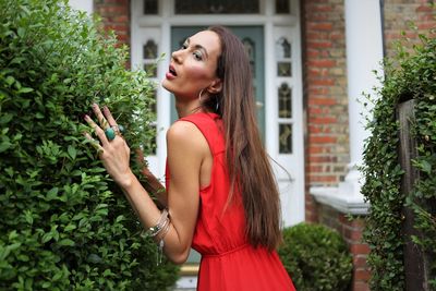 Woman in red dress standing by plants