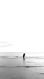 Silhouette person on sea against clear sky