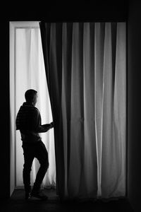 Rear view of man standing against curtain