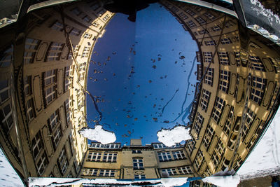 Reflection of buildings on wet car roof during winter