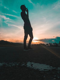 Silhouette man standing on field against sky during sunset