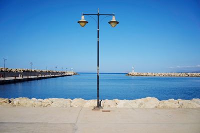 Street by sea against clear blue sky