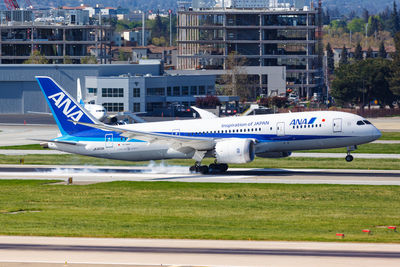 Airplane flying over airport runway against sky