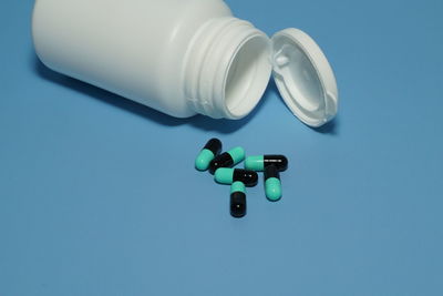 Pills with container on blue background