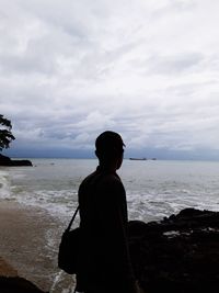 Rear view of man looking at sea against sky