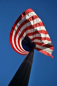 Low angle view of flag against clear blue sky