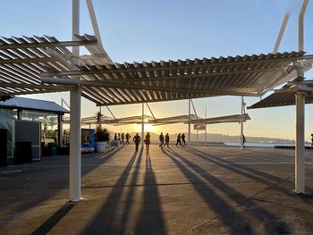 People walking on promenade against sky during sunset