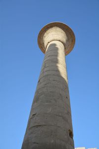 Low angle view of ancient egyptian column against blue sky