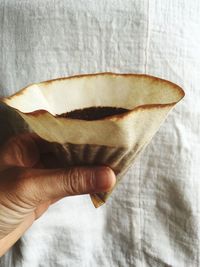 Close-up of hand holding ice cream against wall