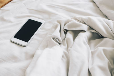 High angle view of mobile phone on bed