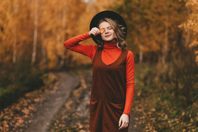 A pretty girl enjoys solitude drinks coffee walks in the autumn forest in nature in fall