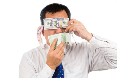 Portrait of young man holding paper against white background