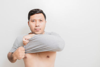 Portrait of young man standing against white background