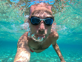 Portrait of shirtless man swimming in sea