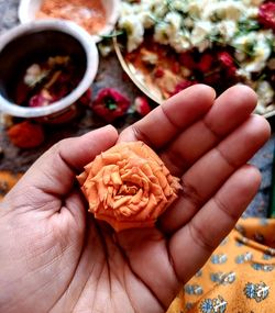 Close up of hand holding a flower for hindu worship