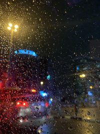 Illuminated street seen through wet glass window