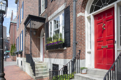 Front of brownstone apartment brick building with windows, shutters, stoops and planters in boston