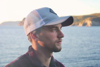 Portrait of young man looking away against sea