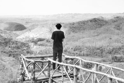 Rear view of man standing on landscape against sky