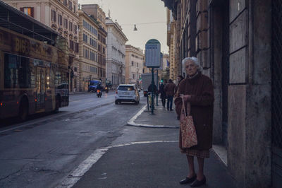 Woman walking on street amidst buildings in city