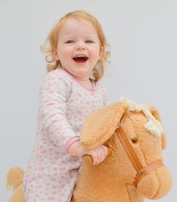 Close-up of cute girl with stuffed toy against white background