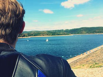 Rear view of man looking at sea against sky