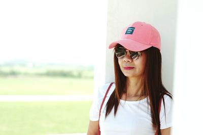 Woman wearing sunglasses and cap by wall