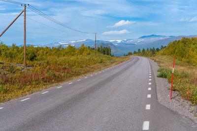 Road with power line next to it in remote wilderness of swedish lapland.fall colors in abisko np.