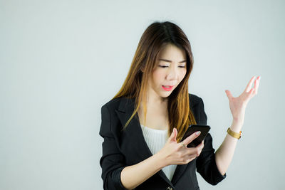 Young woman using mobile phone against white background