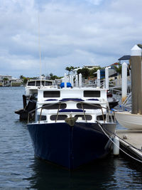 Sailboats moored at harbor against sky