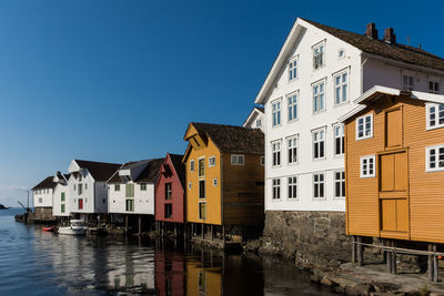 Buildings by river against blue sky